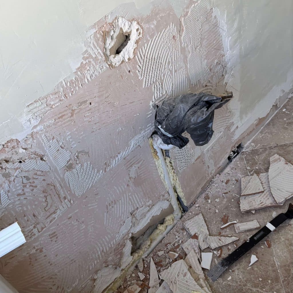 Sink removed from bathroom wall. water pipes hanging out the wall.