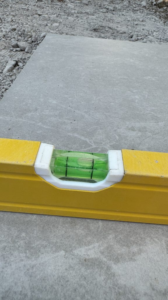 long spirit level showing fall on DIY porcelain patio