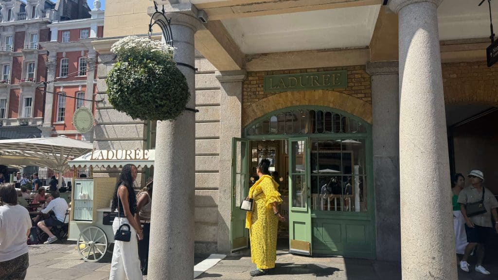 Stylish woman in yellow dress entering boutique in Covent garden. 