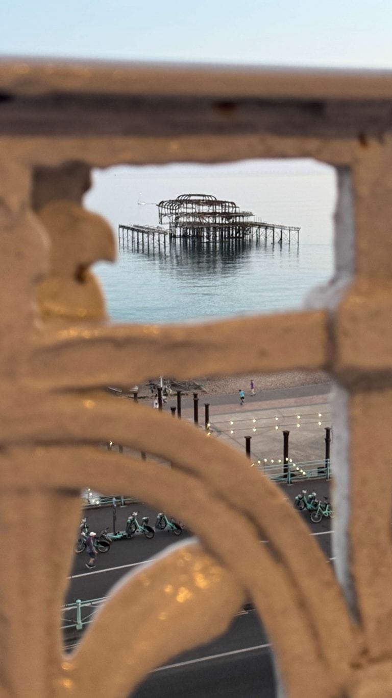 Pier extending into the sea viewed through a decorative railing.